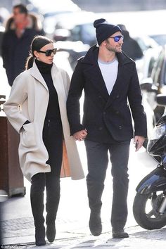 a man and woman walking down the street holding hands