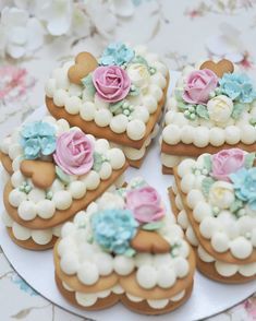 several decorated cookies sitting on top of a white plate with pink, blue and green flowers