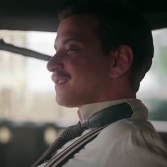 a man in a white shirt and tie sitting in a car