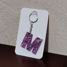 a keychain with the letter m on it is sitting on a table next to a wall