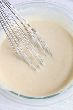 a whisk in a glass bowl filled with batter