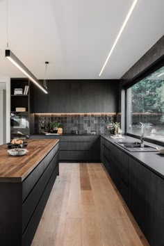 a large kitchen with black cabinets and wooden counter tops, along with an island in the middle