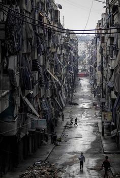 two people are walking down an alley way in the middle of a slum city