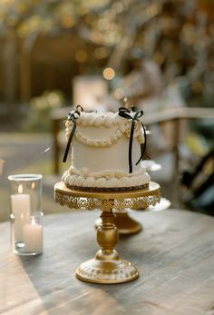 a wedding cake sitting on top of a wooden table next to a glass vase and candle