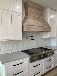 a stove top oven sitting inside of a kitchen next to white cupboards and drawers