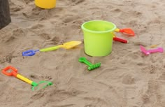 a bucket and shovels are in the sand with other toys around it on the beach