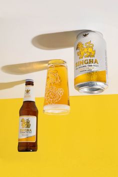 two bottles of beer sitting on top of a yellow and white wall next to a light fixture