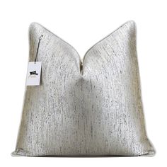 a silver pillow with a white tag on it's front and the back side