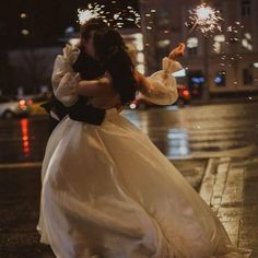 a bride and groom are kissing on the street with sparklers in the air behind them