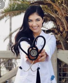 a woman in white coat holding up a stethoscope