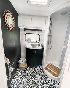 a bathroom with black and white tiles on the floor, sink and shower stall area