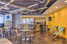 an office with yellow walls and chairs around the tables in front of them is empty