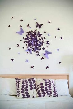 a bed with pillows and purple butterflies on the wall