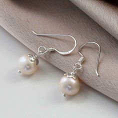 Combining the elegance of silver with the lustre of pearl, our stunning Sterling Silver Round Pearl Dangly Earrings add that perfect finishing touch to any elegant outfit. Symbolising purity and innocence pearl is a favourite for weddings, whether they adorn the ears of a bridesmaid, friend or a treat just for you these flawless Silver Round Pearl Dangly Earrings will give you that chic accessory everyone is looking for. Once considered the most valuable gem pearls are the oldest known precious stone. An old legend says that pearls were created when dew drops filled with moonlight fell into the sea and were swallowed by oysters. All Martha Jackson jewellery comes in a gift box with a small gift card for you to write a message on. If you would like us to write the message for you simply sel Silver Pearl Drop Earrings, Dangly Earrings, Chic Accessories, Spiritual Jewelry, Recycled Sterling Silver, Pearl Drop Earrings, Silver Pearls, Elegant Outfit, Free Jewelry