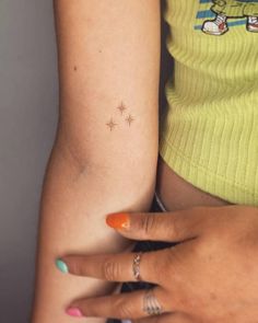 a woman's arm with a tiny star tattoo on the left side of her arm