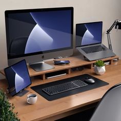 two computer monitors sitting on top of a wooden desk next to a keyboard and mouse