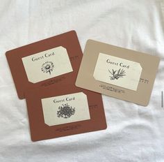 three brown and white cards on top of a white sheet with the words guest card