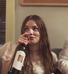 a woman sitting on a couch holding a wine bottle