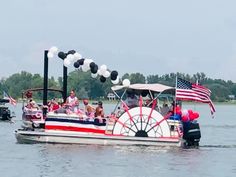 people are riding in a boat on the water with balloons and streamers around it