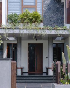 a house with plants growing on the roof and windows over the front door, along with steps leading up to the second floor