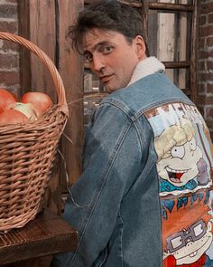 a man standing next to a basket full of apples