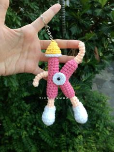 a hand holding a small crocheted keychain in the shape of a cartoon character