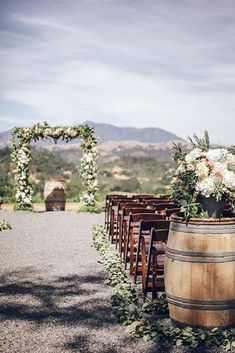 an outdoor ceremony set up with wooden barrels and flowers