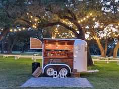 a food truck parked in the grass with lights strung from it's roof and windows