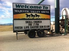 a welcome sign for majestic valley arena in the middle of an open field with horses on it