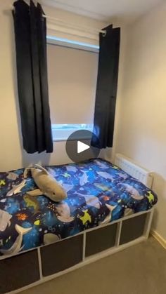 an empty room with a bed, window and curtain in it's corner that has space themed sheets on it