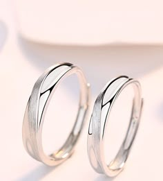 two white gold wedding rings sitting on top of each other in front of a plate