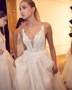 a woman in a wedding dress is walking down the runway with another woman behind her