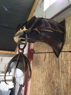 a bat hanging from the side of a wall next to a light bulb on a wire