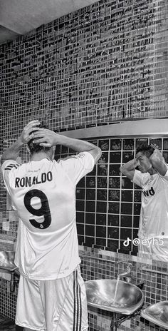 two men are standing in front of a mirror with their hands on their head and one is wearing a jersey