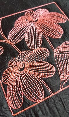 an embroidered black cloth with pink flowers and leaves on the edges is shown in close up