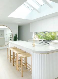 a kitchen with white counter tops and stools in front of a large round mirror