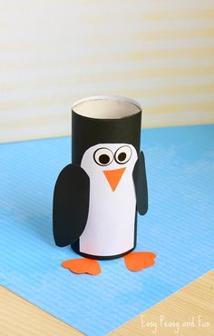 a penguin made out of toilet paper sitting on top of a blue mat with an orange beak