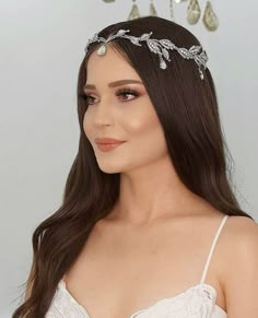 a woman wearing a tiara with pearls and leaves on it's headband