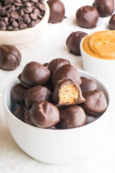 a bowl filled with chocolate covered candy next to bowls of peanut butter and caramel