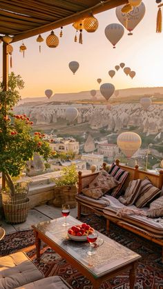 an outdoor living room with hot air balloons flying over the valley and mountains in the distance