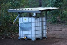 a large white container sitting on top of a dirt road next to a lush green forest