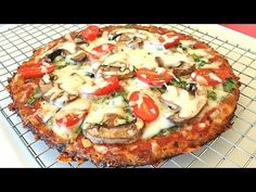 a pizza sitting on top of a cooling rack covered in cheese and toppings,