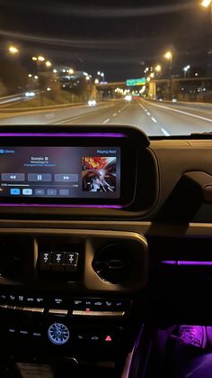 the dashboard of a car with an electronic device in it's center console at night