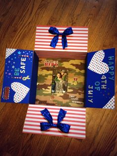 an open book with blue ribbon on the cover and two pictures in it, sitting on top of a wooden table