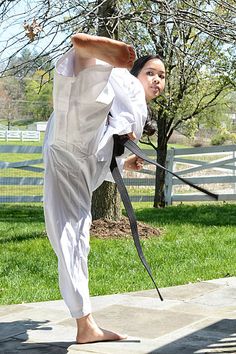 a woman is practicing karate outside in the sun with her hands up and one leg bent forward