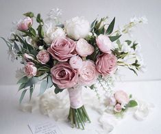 a bouquet of pink and white flowers sitting on top of a table