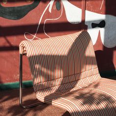 an orange and white striped chair sitting in front of a wall