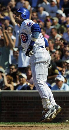 a baseball player running on the field in front of an audience with his arms up