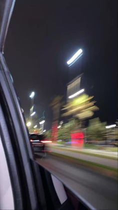 the view from inside a car at night with blurry buildings in the back ground