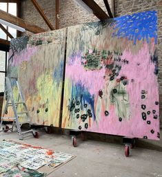 two large paintings are being displayed in an art studio